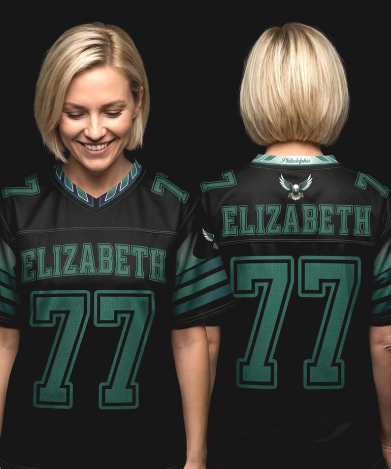 May include: A black jersey featuring the name ELIZABETH and the number 77 in green lettering on the front and back. The jersey includes a V-neck collar with green and white accents, green sleeve stripes, and an eagle emblem on the back neckline.