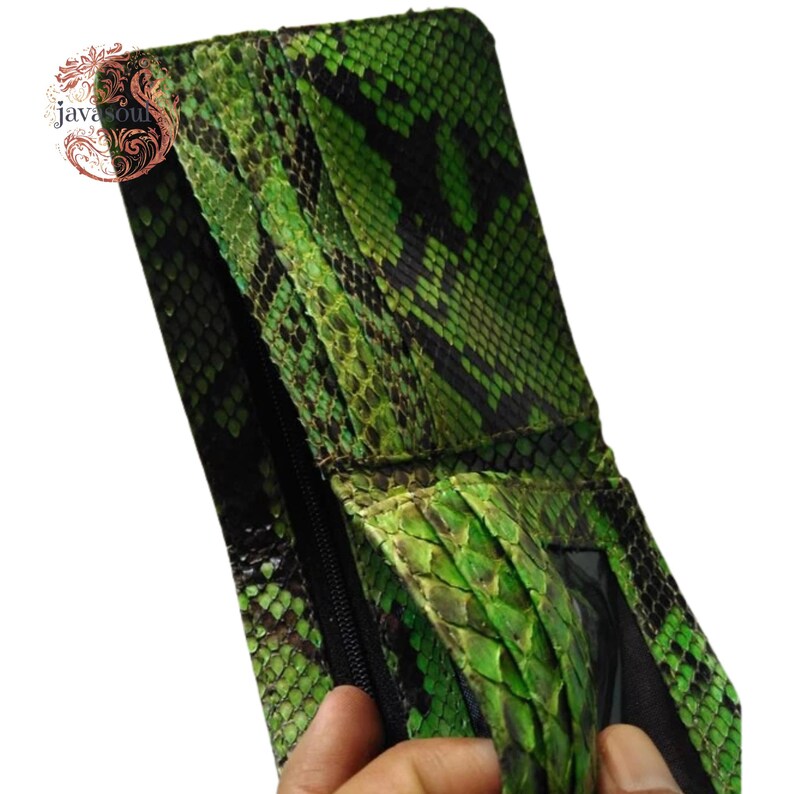 May include: Green and black snakeskin wallet with a zip closure. The wallet has a textured pattern and a bi-fold design. The wallet is made of a reptile skin material.