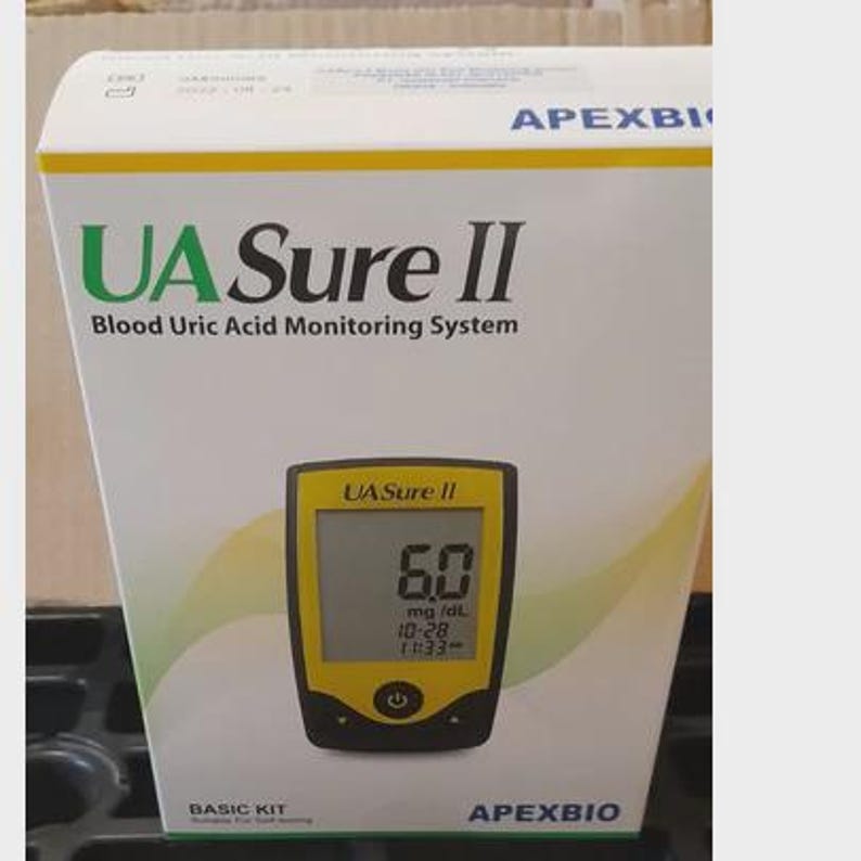 May include: A white box with the text "UA Sure II Blood Uric Acid Monitoring System" in green and black. A yellow and black blood uric acid monitor displays a reading of 6.0 mg/dL. The box also says "BASIC KIT" and "APEXBIO".