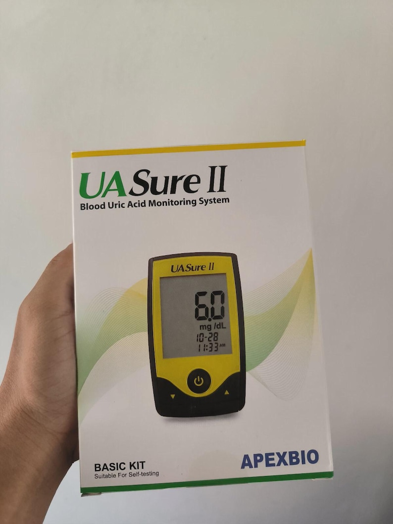 May include: A white box with the text "UA Sure II Blood Uric Acid Monitoring System" and a yellow and black blood uric acid monitor. The monitor displays a reading of 6.0 mg/dL and the time. The box is labeled "BASIC KIT Suitable For Self-testing."