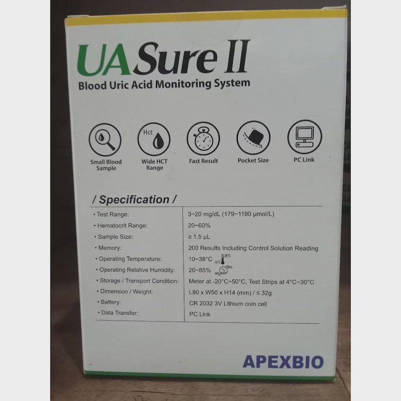 May include: A white box with green text reading "UA Sure II Blood Uric Acid Monitoring System." The box includes icons and specifications such as test range, sample size, and operating temperature. The brand name "APEXBIO" is printed at the bottom.