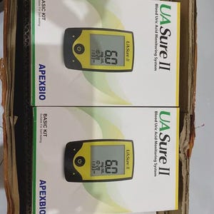 May include: A cardboard box containing multiple boxes of the UA Sure II Blood Uric Acid Monitoring System. Each box features a yellow and black meter displaying a reading of 6.0 mg/dL. The boxes also display the ApexBio logo.