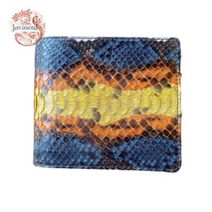 May include: A bi-fold wallet with a snakeskin pattern in shades of blue, orange, and yellow. The wallet has a rectangular shape and a textured surface. The brand name "javasoul" is visible in the upper left corner.