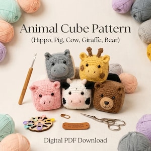 May include: A digital PDF pattern for crocheted animal cubes featuring a hippo, pig, cow, giraffe, and bear. The image displays five finished cube-shaped plush toys, a wooden crochet hook, a circular stitch marker holder, and metal scissors.