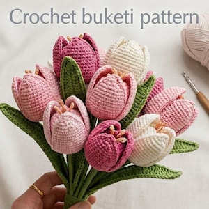 May include: A handmade bouquet of crocheted tulips in pink and white, with green leaves. The text "Crochet buketi pattern" is at the top. A crochet hook and ball of yarn are visible in the background.
