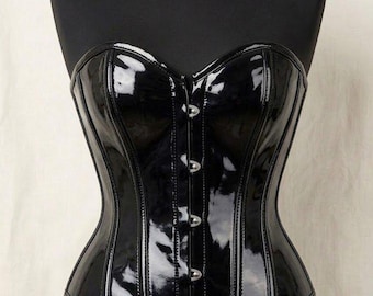 May include: A black corset with a glossy, patent-like finish and a sweetheart neckline. The garment features vertical paneling and a front closure with silver-toned metal busk clasps, providing a structured, form-fitting silhouette on a mannequin.