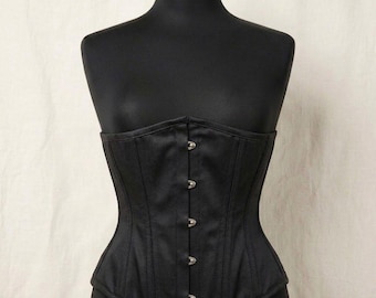 May include: A black corset featuring a structured bodice with vertical paneling and a front closure consisting of five silver-toned metal busk clasps. The garment is displayed on a black mannequin torso, showcasing a fitted silhouette.