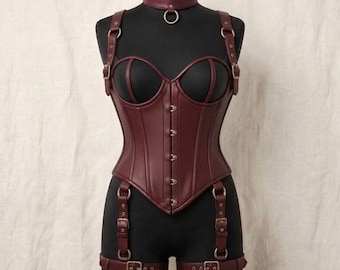 May include: A dark burgundy faux leather corset featuring a sweetheart neckline, front metal hook closures, and an integrated choker with a central ring. The garment includes adjustable shoulder straps and attached thigh garter straps with buckles.