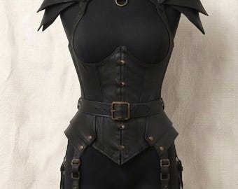 May include: A black leather-like corset top featuring layered shoulder pauldrons, a high neck collar with a metal ring, and a front button closure. The garment includes an integrated waist belt with a buckle and attached leg garter straps.