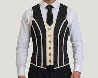 May include: A structured waistcoat featuring a black damask patterned fabric on the sides and a cream-colored center panel. The garment includes vertical cream piping, a front hook-and-eye closure, and a fitted silhouette worn over a white shirt.