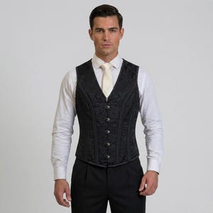 Può includere: Un gilet nero con motivo floreale e bottoni argentati, indossato sopra una camicia bianca e pantaloni neri. Il gilet, dalla vestibilità aderente, è adatto per occasioni formali.