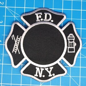 Puede incluir: Parche bordado en blanco y negro con forma de cruz de Malta. El parche presenta las letras "F.D." en la parte superior y "N.Y." en la parte inferior. El círculo central es negro y los brazos de la cruz tienen símbolos de los bomberos.