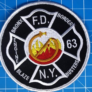 May include: A circular black and white embroidered patch with the text "BRONX ENGINE BLAZE N.Y. BORDER BUSTERS 63 F.D." in white. The central design features a fire hose and flames.