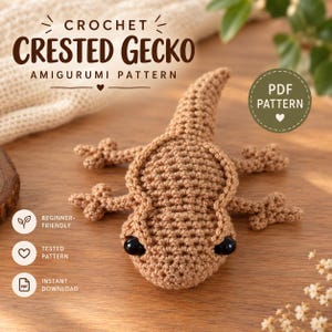 Może przedstawiać: Szydełkowane amigurumi gekona orzęsionego w kolorze opalenizny z czarnymi oczami z koralików. Tekst głosi CROCHET CRESTED GECKO AMIGURUMI PATTERN, PDF PATTERN, BEGINNER-FRIENDLY, TESTED PATTERN oraz INSTANT DOWNLOAD. Gekon ma teksturowaną powierzchnię.