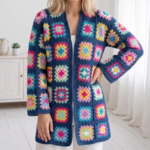 May include: A long-sleeved cardigan made of dark blue crochet granny squares. Each square features a vibrant, multi-colored floral pattern in shades of pink, yellow, light blue, and white. The garment has an open front design and a straight hem.