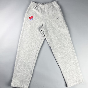 May include: Grey sweatpants with a red and blue maple leaf logo on the left leg and a black Nike swoosh logo on the right leg.