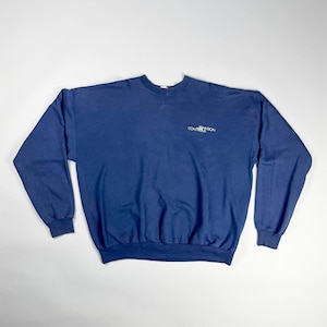 以下が含まれることがあります： 長袖のネイビーブルーのスウェットシャツ。クルーネックのスウェットシャツには、左胸上部に白で「Convention」の文字がプリントされています。スウェットシャツは柔らかい素材でできており、カジュアルウェアに適しています。