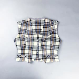 May include: A cream, blue, brown, and black plaid sleeveless vest with a button-down front. The vest features a V-neck and two small pockets. The buttons are small and black.