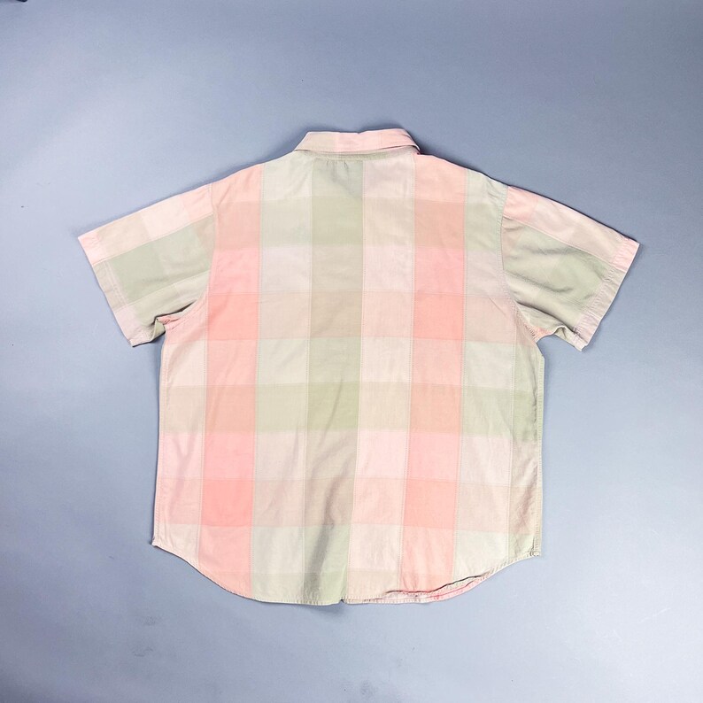 May include: A pink and green plaid short-sleeved button-up shirt.