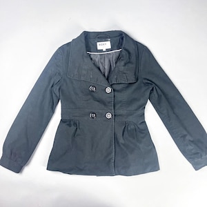 May include: A black Roxy jacket with a double-breasted design. The jacket features a notched collar, long sleeves, and a fitted waist. The Roxy label is visible on the back of the collar. The jacket has four black buttons and a peplum hem.