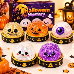 Peut inclure: Cinq jouets spongieux sur le thème d'Halloween aux designs transparents, pailletés et à motifs, incluant une citrouille, un globe oculaire et des silhouettes de fantômes. Chaque jouet repose sur un petit socle noir orné de fantômes jaunes.