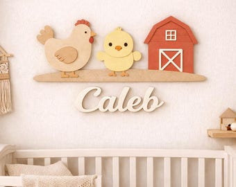 May include: A wall-mounted wooden sign featuring a tan chicken, a yellow chick, and a red barn on a horizontal base. Below the base, the name Caleb is written in white cursive script. The sign is positioned above a white wooden crib.