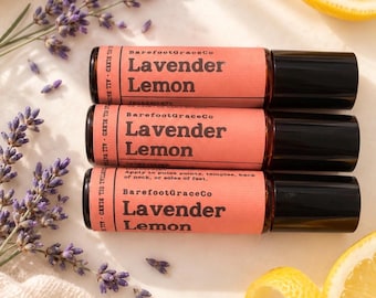 May include: Three amber glass roller bottles with black caps, each featuring a peach-coloured label with the text BarefootGraceCo Lavender Lemon. The labels include instructions to apply to pulse points, temples, back of neck, or soles of feet.