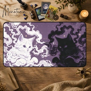 Puede incluir: Una alfombrilla de escritorio rectangular con fondo morado que muestra un gato blanco a la izquierda y un gato negro a la derecha, rodeados de humo arremolinado y pequeñas estrellas. El diseño incluye motivos de media luna y una estética mística.