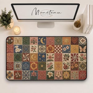 May include: A rectangular desk mat featuring a grid of square tiles with diverse illustrations including flowers, celestial bodies like moons and suns, butterflies, and geometric patterns in shades of red, blue, green, and gold on a cream background.