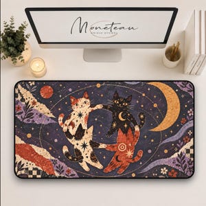 May include: A rectangular desk mat featuring a dark purple celestial background with three cats dancing in a circle. The cats are white with black spots, solid black, and orange, decorated with stars and moons. A large crescent moon and floral accents frame the scene.
