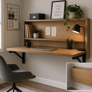 May include: A wall-mounted wooden desk with a black metal support, featuring a shelf, a black desk lamp, and a gray office chair. The desk has a laptop, a black mug, and a pen holder. A framed print reads "FOCUS PLAN EXECUTE REPEAT."