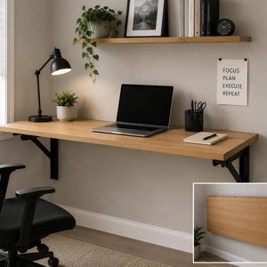 May include: A light wood-effect wall-mounted desk with black metal brackets. A black desk lamp, laptop, and office supplies are on the desk. A black office chair is in front. A small inset shows the desk folded.