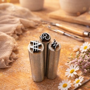 Può includere: Una tazza di ceramica bianca con manico nero e la scritta "But First, Coffee" in grassetto nero. La tazza è appoggiata su una superficie di legno.