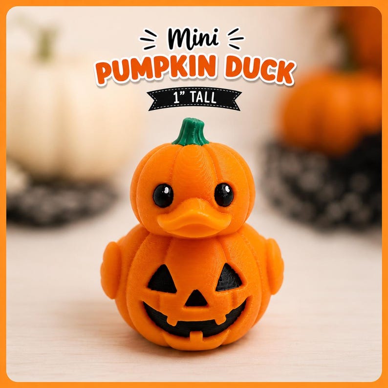May include: A small orange duck-shaped figure with a pumpkin-like body and a green stem on its head. The front features a carved jack-o'-lantern face with black triangular eyes and a jagged mouth. Text above reads Mini PUMPKIN DUCK 1" TALL.