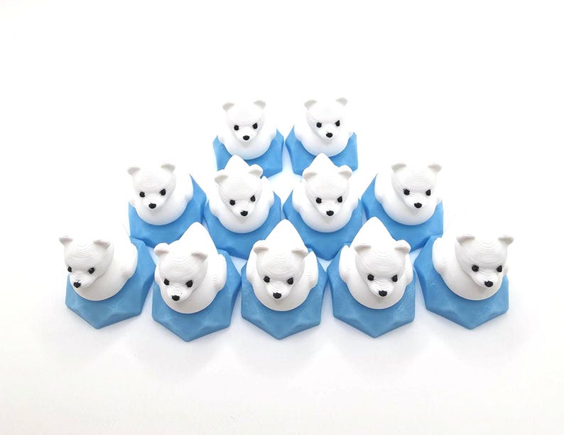May include: A collection of eleven small, white polar bear figurines, each mounted on a light blue, faceted hexagonal base. The bears have black eyes and noses, and are arranged in a triangular formation against a plain white background.