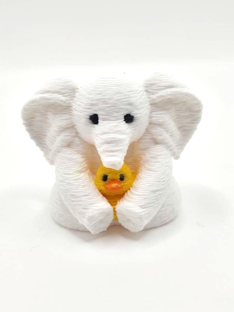 Mini towel animal elephant holding a yellow duck, 3D printed collectible by Florida Cruise Ducks. White elephant design with textured towel-like appearance, approximately 1 inch tall. Shown from multiple angles including front, side, back, hand-held size comparison, and marker comparison. Perfect for cruise duck hiding, cruise gifts, duck exchanges, party favors, and miniature collectibles. Exclusive Florida Cruise Ducks design.