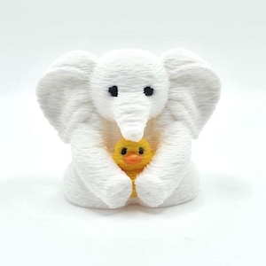 Mini towel animal elephant holding a yellow duck, 3D printed collectible by Florida Cruise Ducks. White elephant design with textured towel-like appearance, approximately 1 inch tall. Shown from multiple angles including front, side, back, hand-held size comparison, and marker comparison. Perfect for cruise duck hiding, cruise gifts, duck exchanges, party favors, and miniature collectibles. Exclusive Florida Cruise Ducks design.
