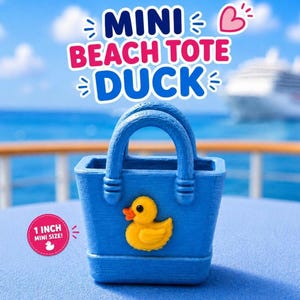 May include: A blue mini beach tote bag featuring a yellow duck emblem on the front. The bag has two handles and a textured surface. A pink circular graphic on the left side displays the text 1 INCH MINI SIZE! with a small white duck icon.