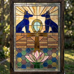 Può includere: Pannello in vetro colorato con due figure di sciacalli blu che fiancheggiano un simbolo ankh. L'opera d'arte include un fiore di loto nella parte inferiore e un motivo geometrico. Il pannello è incorniciato in legno scuro.
