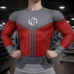 Puede incluir: Una camiseta de compresión gris y roja con cuello redondo y mangas largas. La camiseta presenta una parte superior del pecho y mangas grises, un torso rojo y un diseño gris en la cintura. Un logotipo blanco está en la parte superior del pecho.