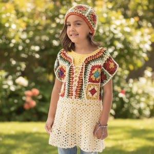 Peut inclure: Une tunique en crochet avec un corsage composé de carrés granny multicolores, un laçage sur le devant et une jupe en maille ajourée couleur crème. L'ensemble est assorti à un bonnet en crochet présentant un motif floral de carrés granny.