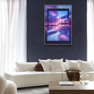 May include: A framed art print depicting a colorful, abstract cityscape with reflections. The artwork features shades of blue, purple, and pink. The print is displayed on a dark blue wall above a white sofa with pillows and a wooden coffee table.