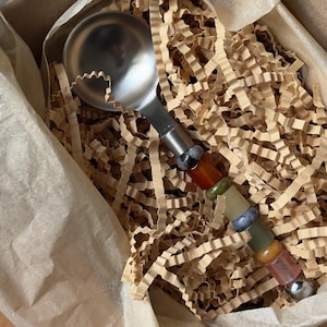 Pu&ograve; includere: Una paletta per gelato in acciaio inossidabile con un manico decorativo in pietre preziose colorate. La paletta &egrave; presentata in una scatola di cartone con carta marrone e materiale di imballaggio sminuzzato.