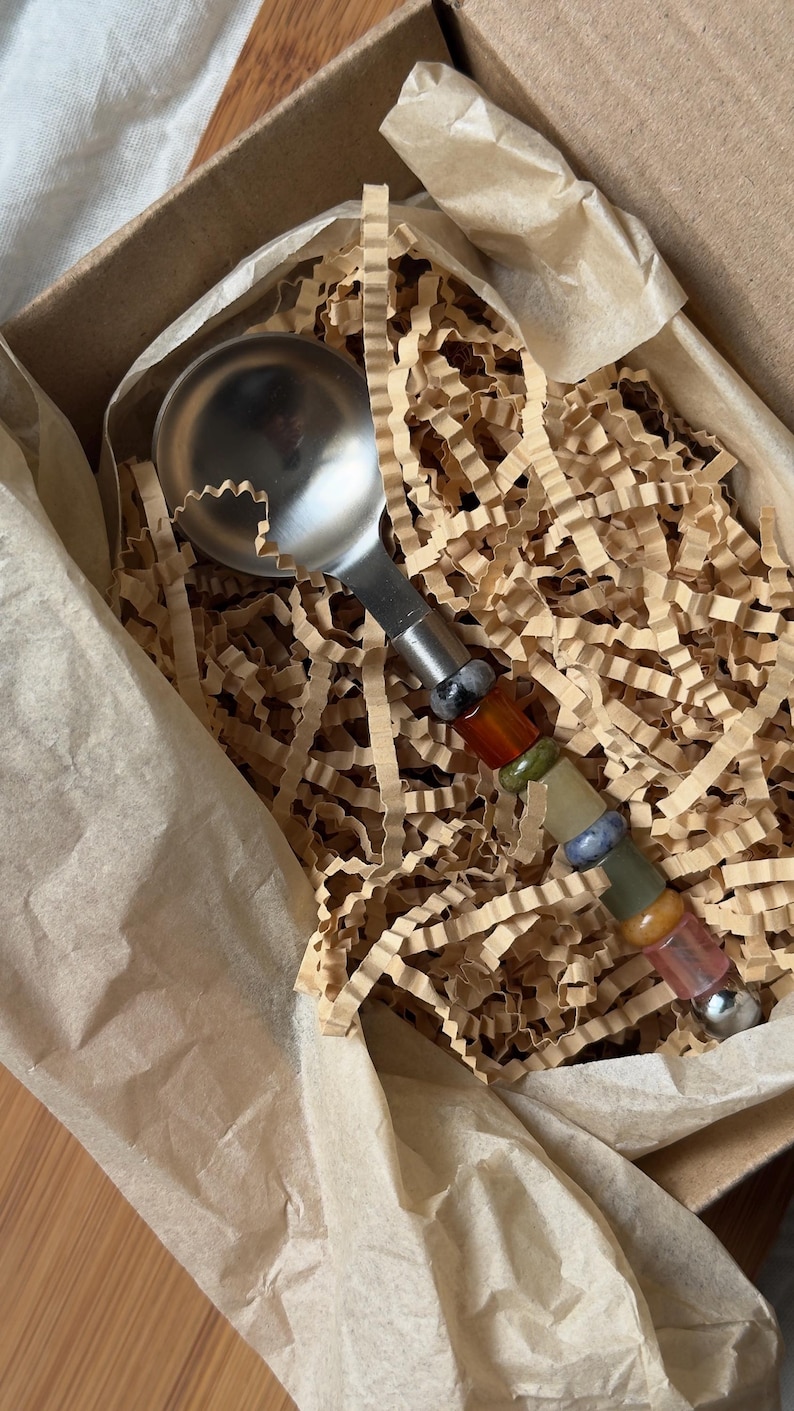Pu&ograve; includere: Una paletta per gelato in acciaio inossidabile con un manico decorativo in pietre preziose colorate. La paletta &egrave; presentata in una scatola di cartone con carta marrone e materiale di imballaggio sminuzzato.