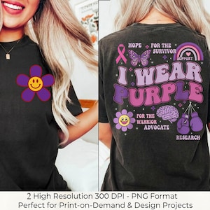 Puede incluir: Camiseta negra con una flor morada en la parte delantera. La parte trasera de la camiseta presenta el texto "I Wear Purple" con gráficos de apoyo, incluyendo una cinta, una mariposa, un arcoíris y guantes de boxeo. Ideal para proyectos de impresión bajo demanda.