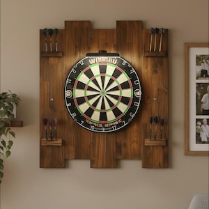 Peut inclure: Une cible de fléchettes circulaire Winmau montée sur un panneau arrière en bois brun foncé avec des étagères intégrées contenant douze fléchettes. La cible présente un anneau numéroté standard, un centre et un éclairage noir fixé au sommet.