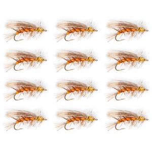 May include: Twelve artificial fishing flies. Each fly features a curved hook, a body of orange and yellow thread, and brown and tan feather wings. The flies are arranged in three rows of four on a white background.
