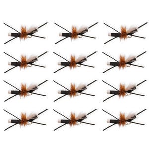 May include: A set of twelve identical fishing flies arranged in a grid. Each fly features a black cylindrical body, a white tip, brown hackle fibres, and long, thin black rubber legs extending outward in an X-shaped pattern for fly fishing.