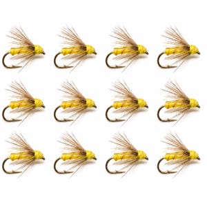 May include: A set of twelve fishing flies arranged in a grid. Each fly features a bright yellow body wrapped in thread, a sharp metal hook, and brown hackle feathers extending from the top to mimic the appearance of an insect wing.