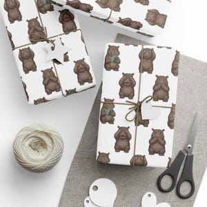 May include: Gift wrap featuring a repeating pattern of cartoon hippos in various poses on a white background. The wrapped gifts are tied with twine and adorned with paper tags. A ball of twine, scissors, and blank tags are also visible.